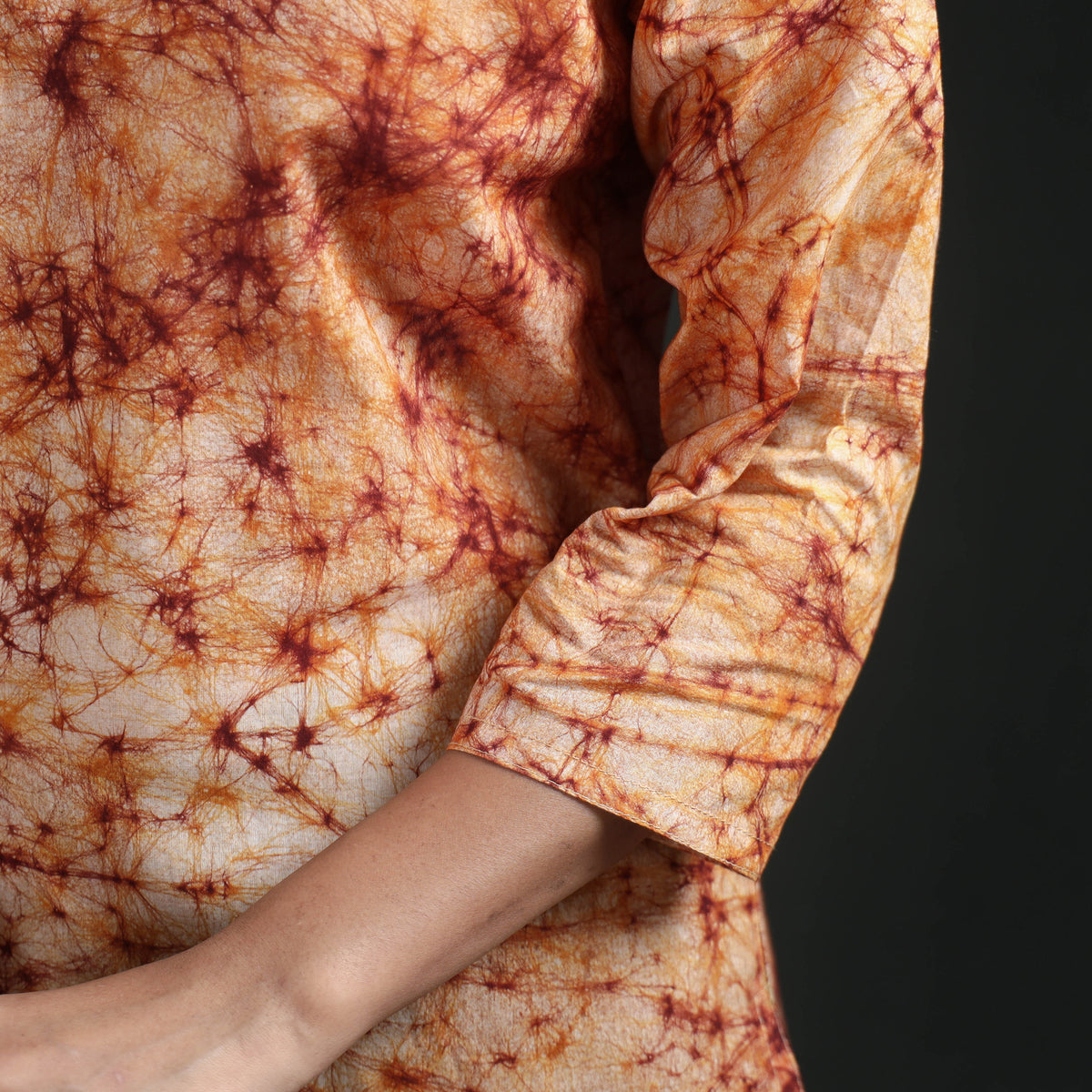 Three-quarter sleeve of the peach cream kurta, plain edge under the orange web print