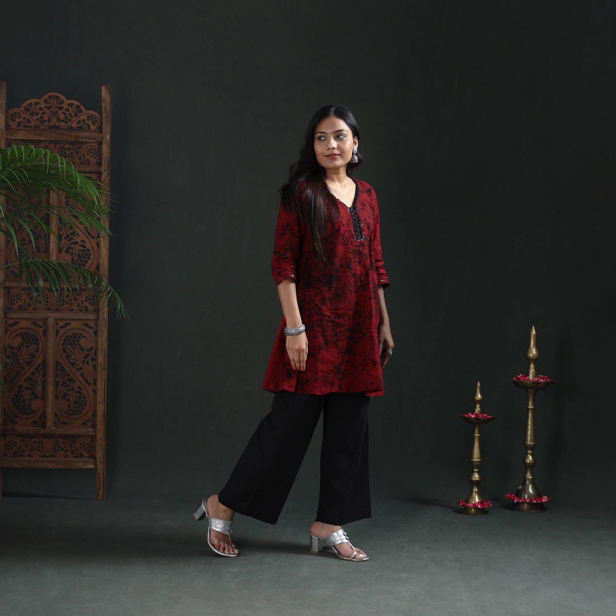 Mid-step three-quarter view of the maroon Batik kurta over black wide-leg trousers, casual wear