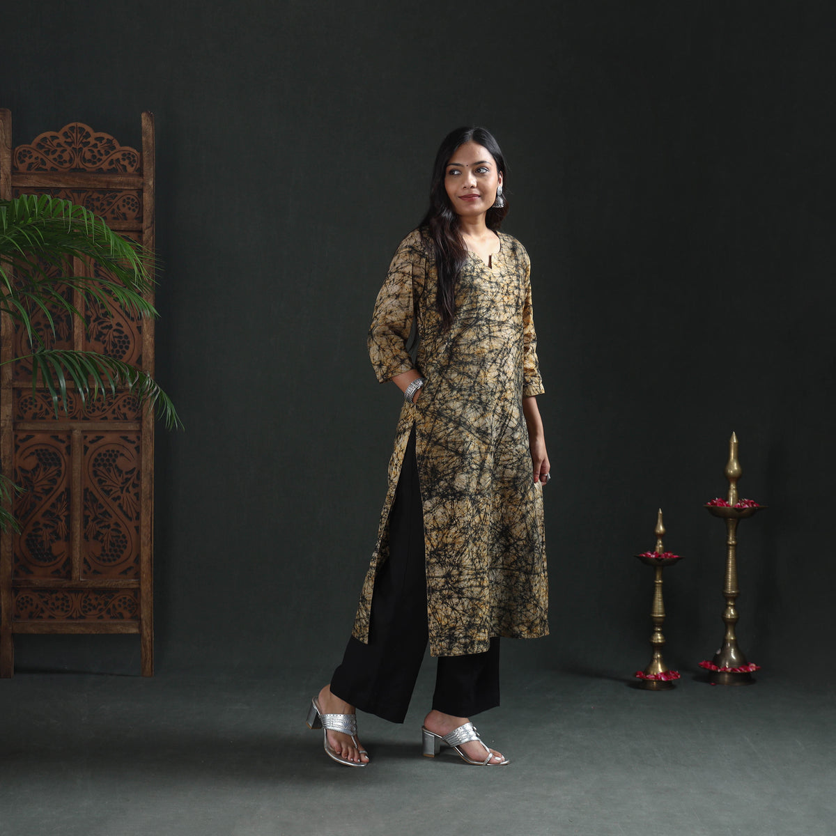 Front three-quarter view of a beige batik cotton kurta with a black web print, hand in the pocket