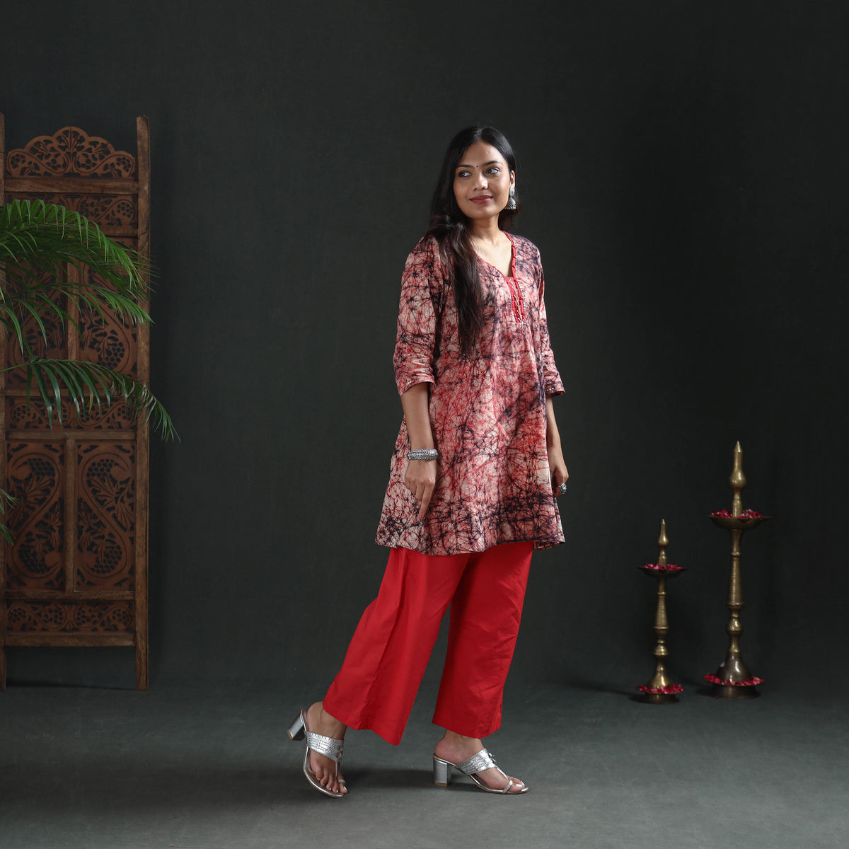 Three-quarter front view of the cream and red batik kurta worn with red wide-leg trousers, casual wear