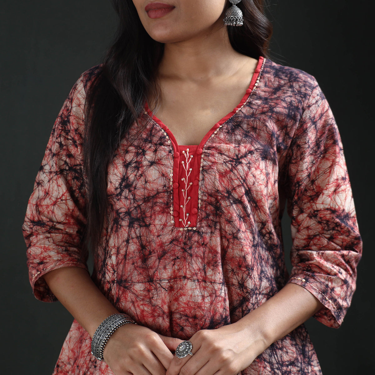 Red neck panel with white leaf-vine embroidery on the cream batik kurta