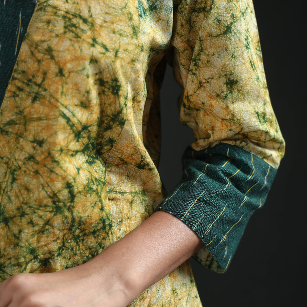 Sleeve detail of the yellow kurta: wide dark green cuff with fine pale dashes
