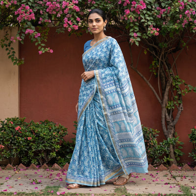 Blue Bagh Hand Block Print Natural Dyed Maheshwari Silk Zari Border Saree, worn by a woman walking in a garden courtyard, AI visual of the saree, iTokri