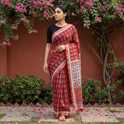 Red Bagh Hand Block Print Natural Dyed Maheshwari Silk Zari Border Saree, worn by a woman walking in a garden courtyard, AI visual of the saree, iTokri