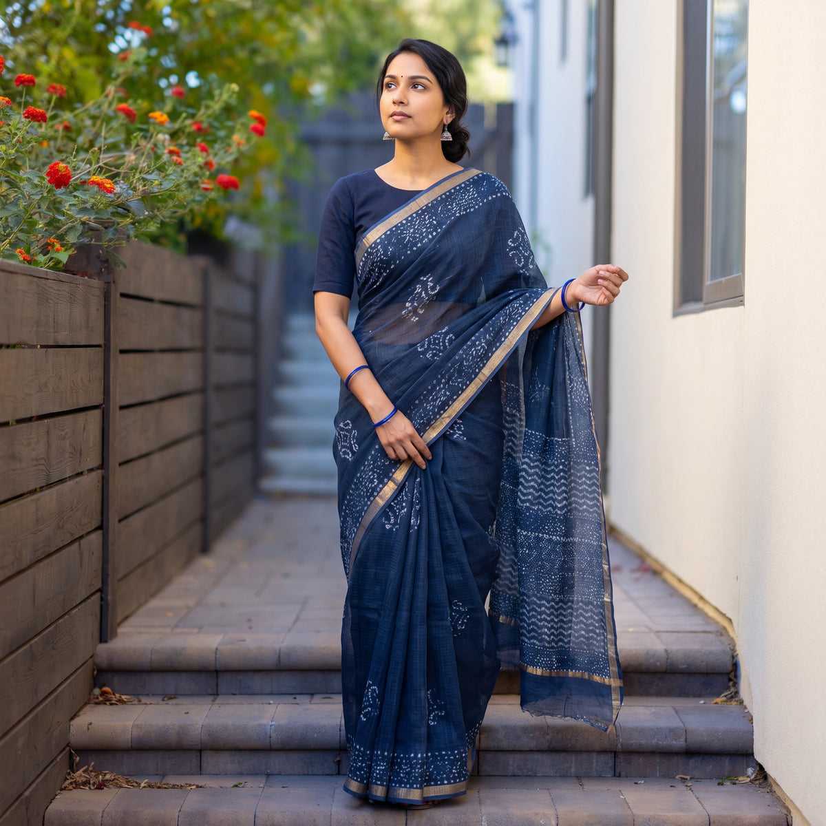 Navy Blue Batik Hand Block Print Kota Doria Cotton Saree, worn by a woman on garden steps beside a white wall, AI visual of the saree, iTokri