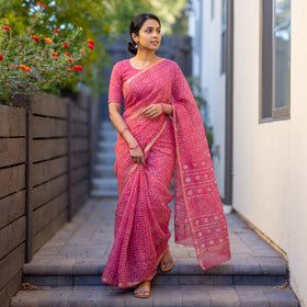 Pink Batik Hand Block Print Kota Doria Cotton Saree, worn by a woman on garden steps beside a white wall, AI visual of the saree, iTokri