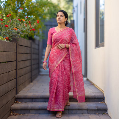Pink Batik Hand Block Print Kota Doria Cotton Saree, worn by a woman on garden steps beside a white wall, AI visual of the saree, iTokri