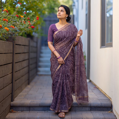 Purple Batik Hand Block Print Kota Doria Cotton Saree, worn by a woman on garden steps beside a white wall, AI visual of the saree, iTokri