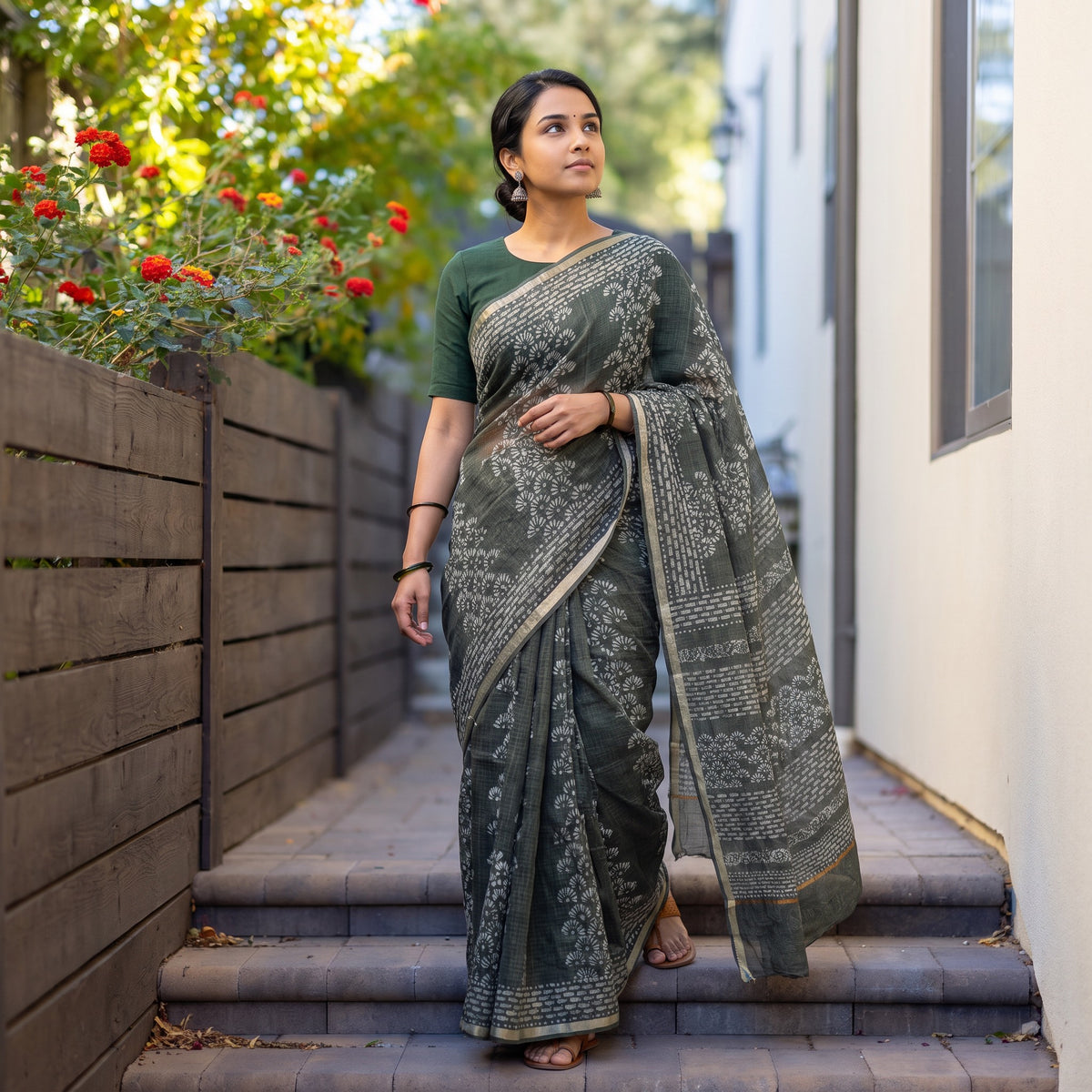 Grey Batik Hand Block Print Kota Doria Cotton Saree, worn by a woman on garden steps beside a white wall, AI visual of the saree, iTokri