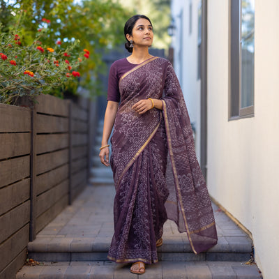 Purple Batik Hand Block Print Kota Doria Cotton Saree, worn by a woman on garden steps beside a white wall, AI visual of the saree, iTokri