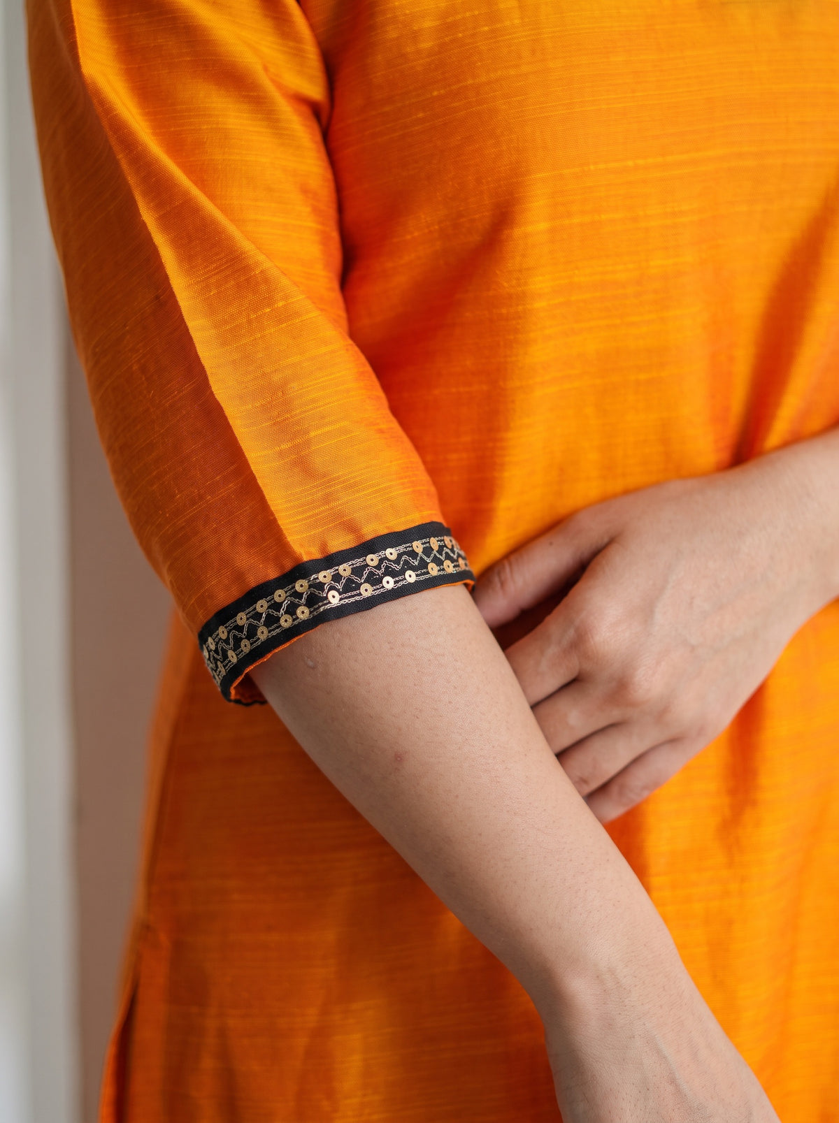 Orange Plain Art Silk Sequin Trim Kurta, sleeve close-up, 3/4 sleeves, black-gold zig-zag sequin trim, AI visual of the kurta, iTokri
