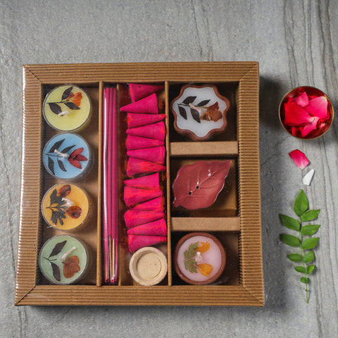 A cardboard gift set with various incense sticks, incense cones, and candles displayed in an organized manner. The set include items in different colors.